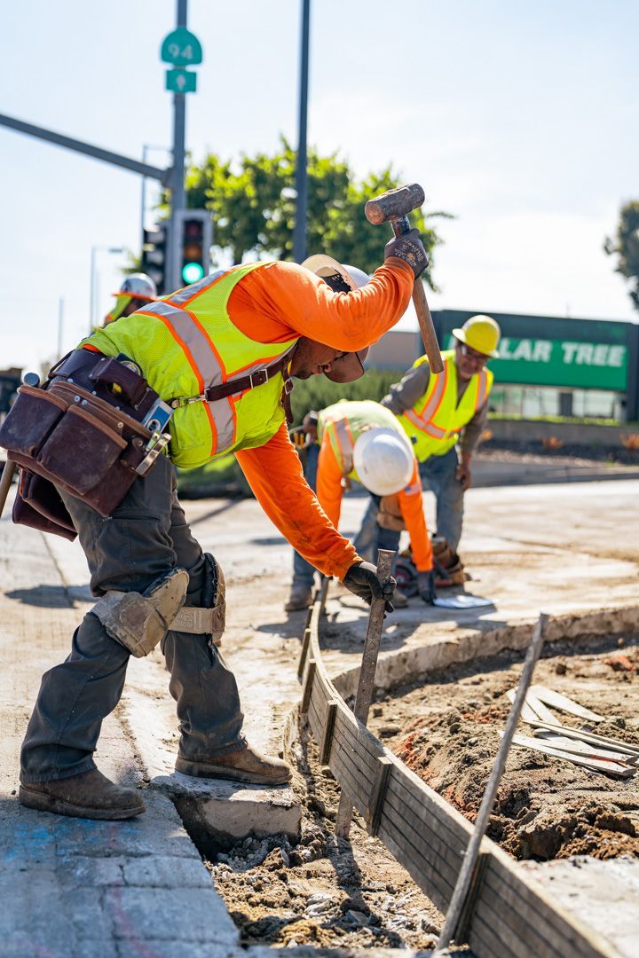 A group of construction workers are working on a sidewalk.