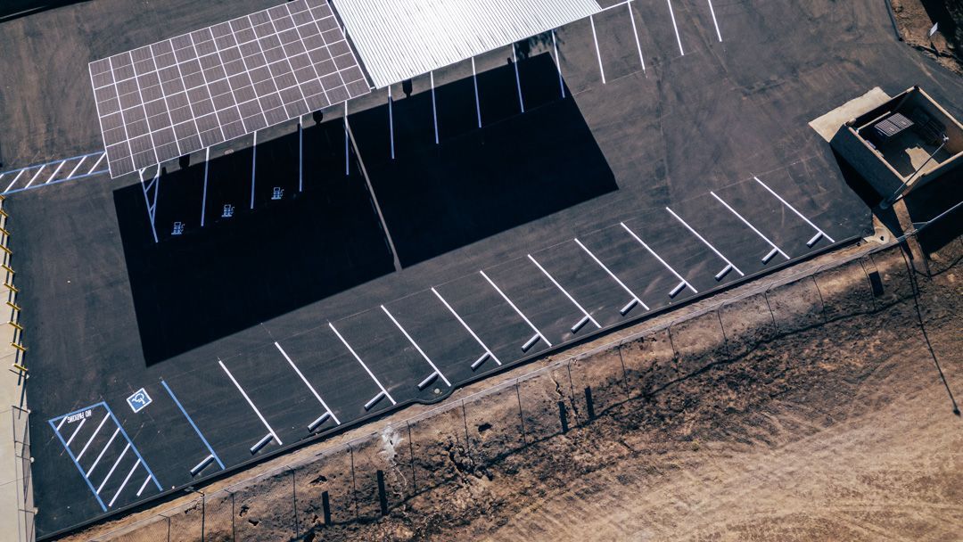 An aerial view of a parking lot with a building in the background.