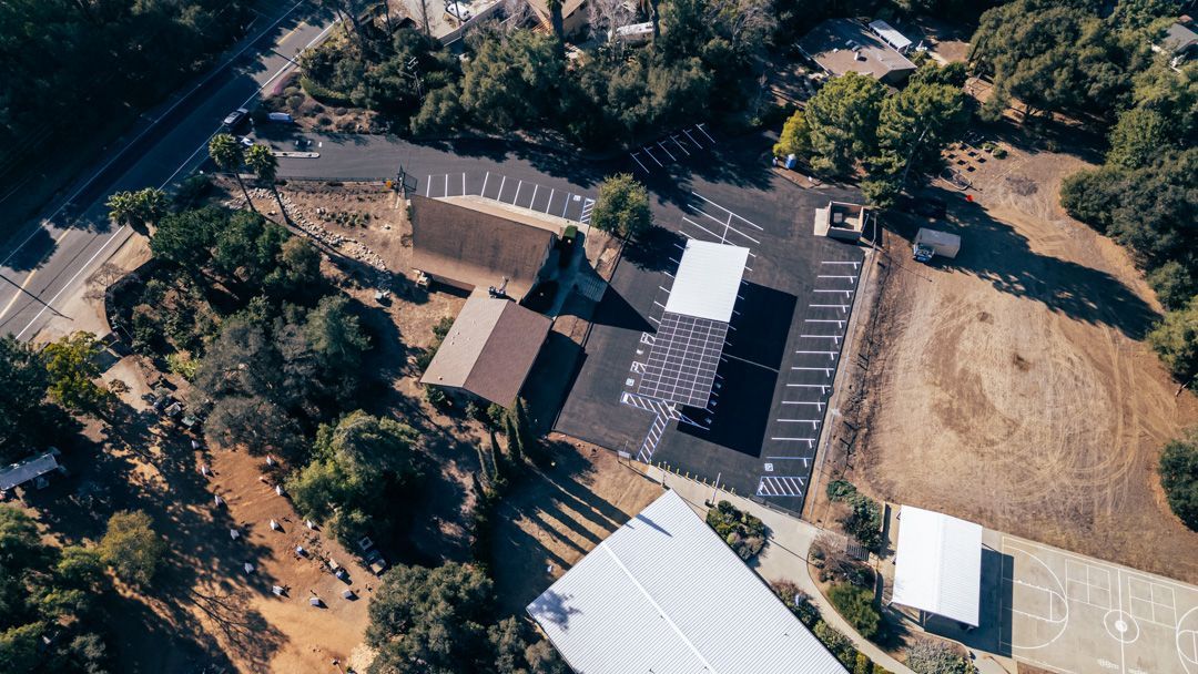 An aerial view of a large building surrounded by trees and a parking lot.