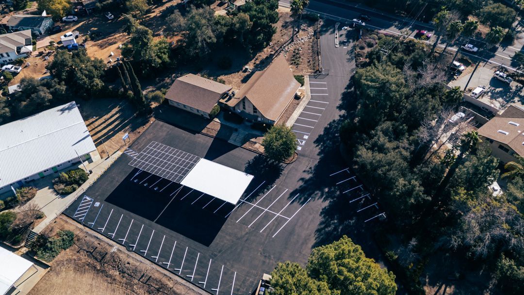 An aerial view of a parking lot surrounded by trees and buildings.