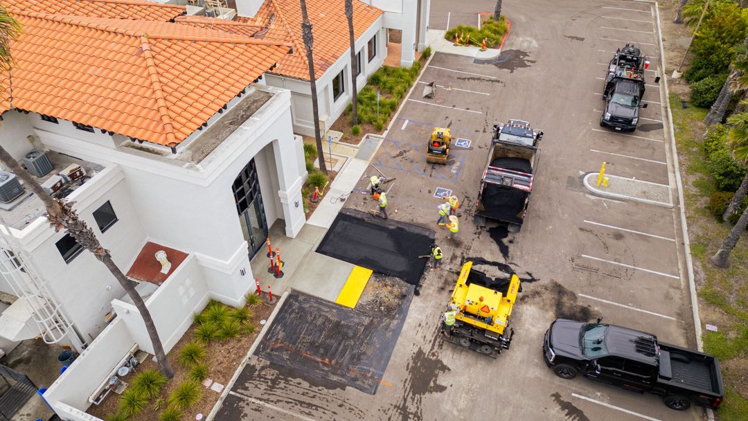 An aerial view of a parking lot being paved in front of a building.