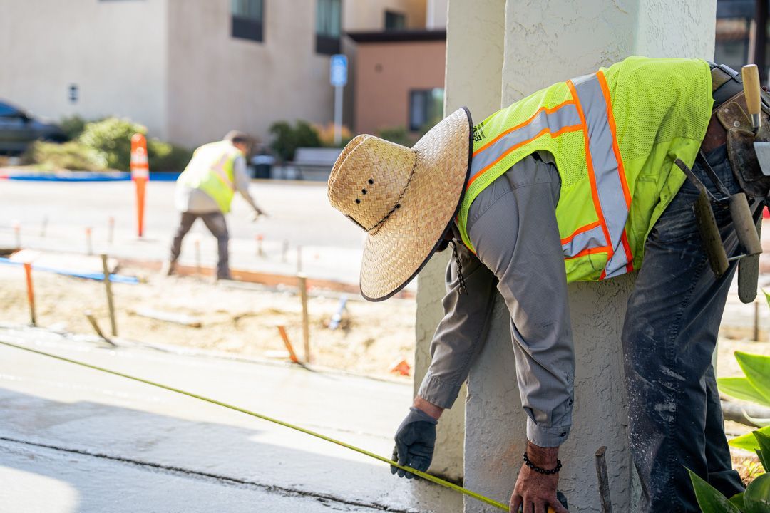A construction worker is measuring a pole with a tape measure.