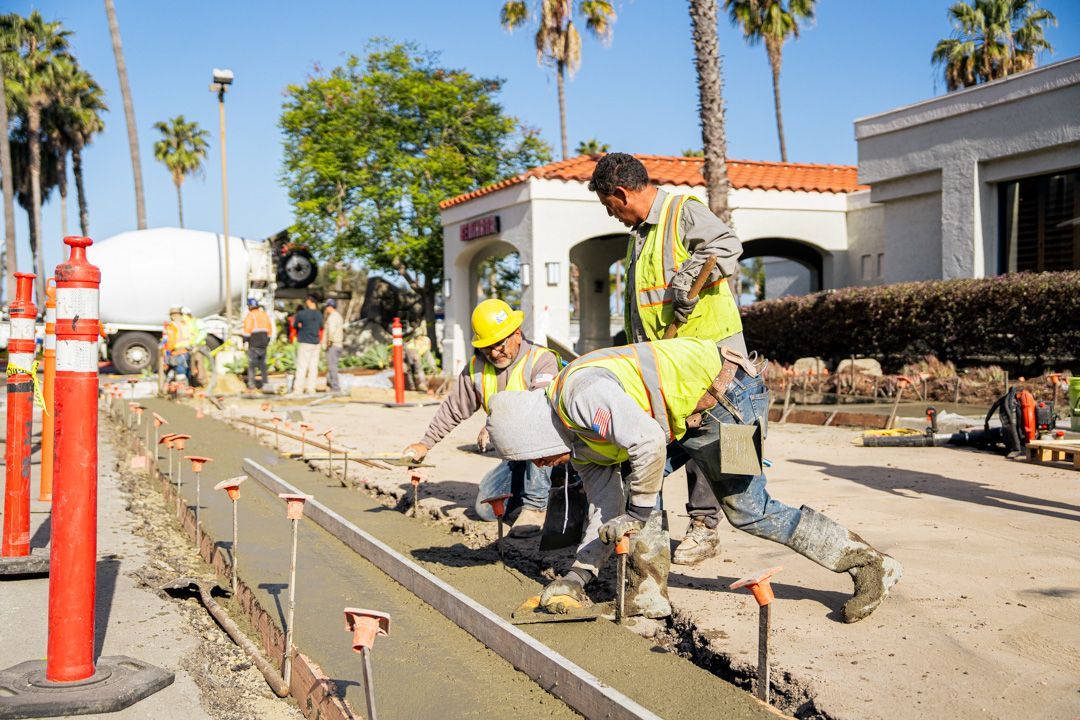 A group of construction workers are working on a sidewalk.
