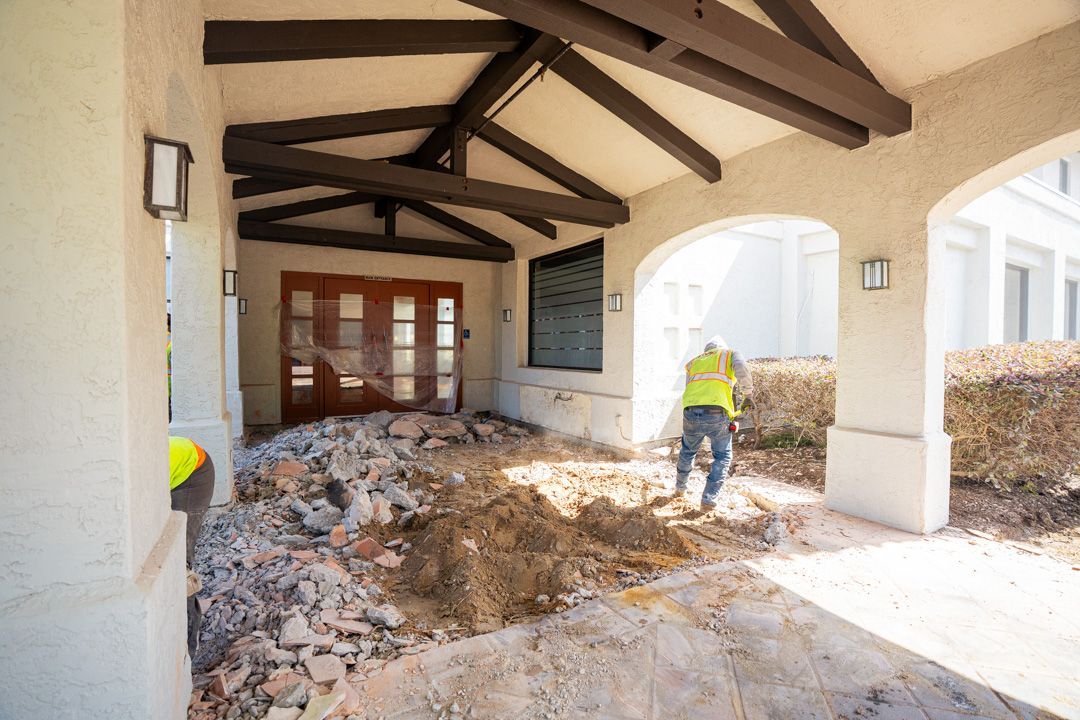 A man is digging in the dirt in front of a building.