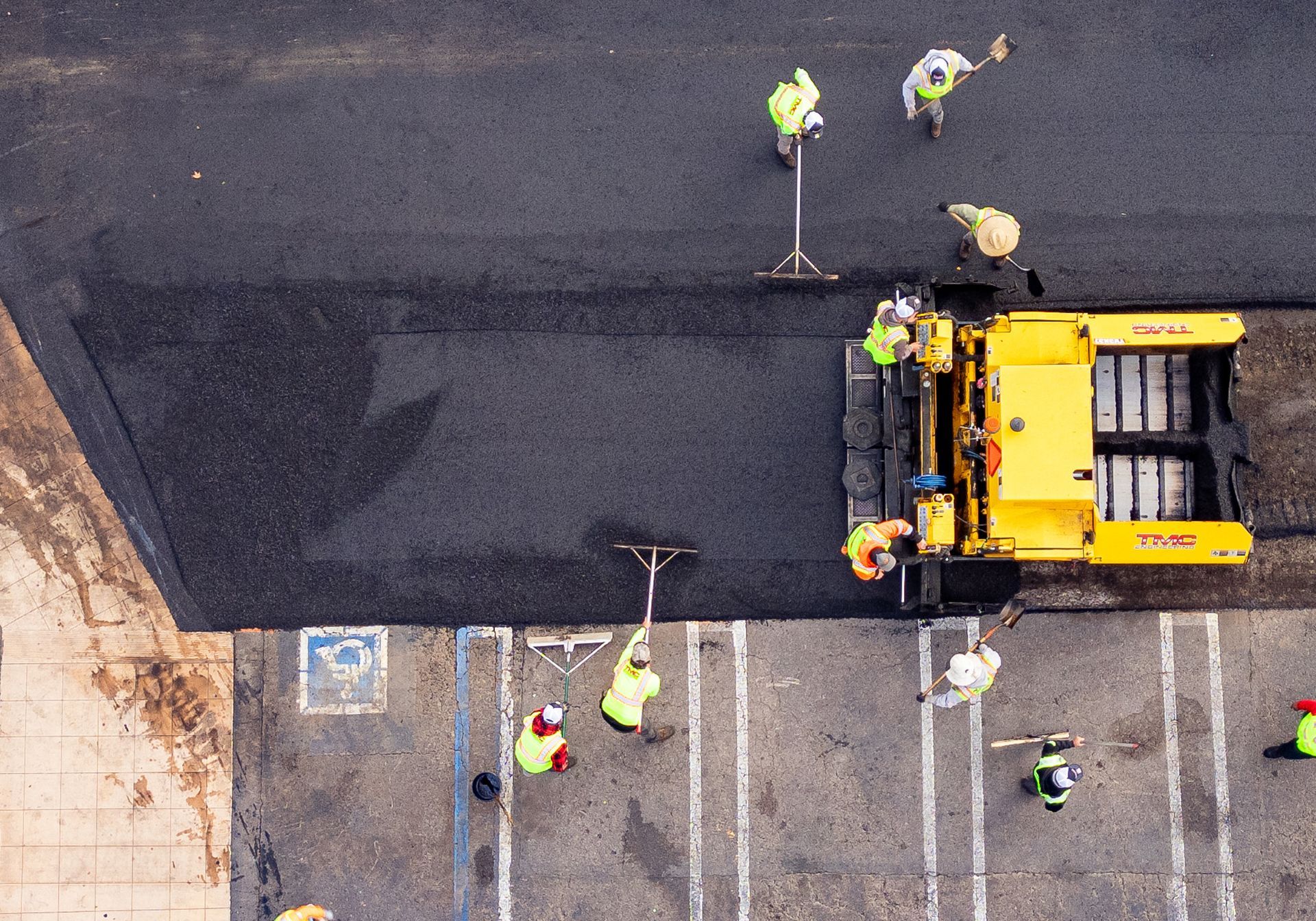 A group of construction workers are working on a parking lot.