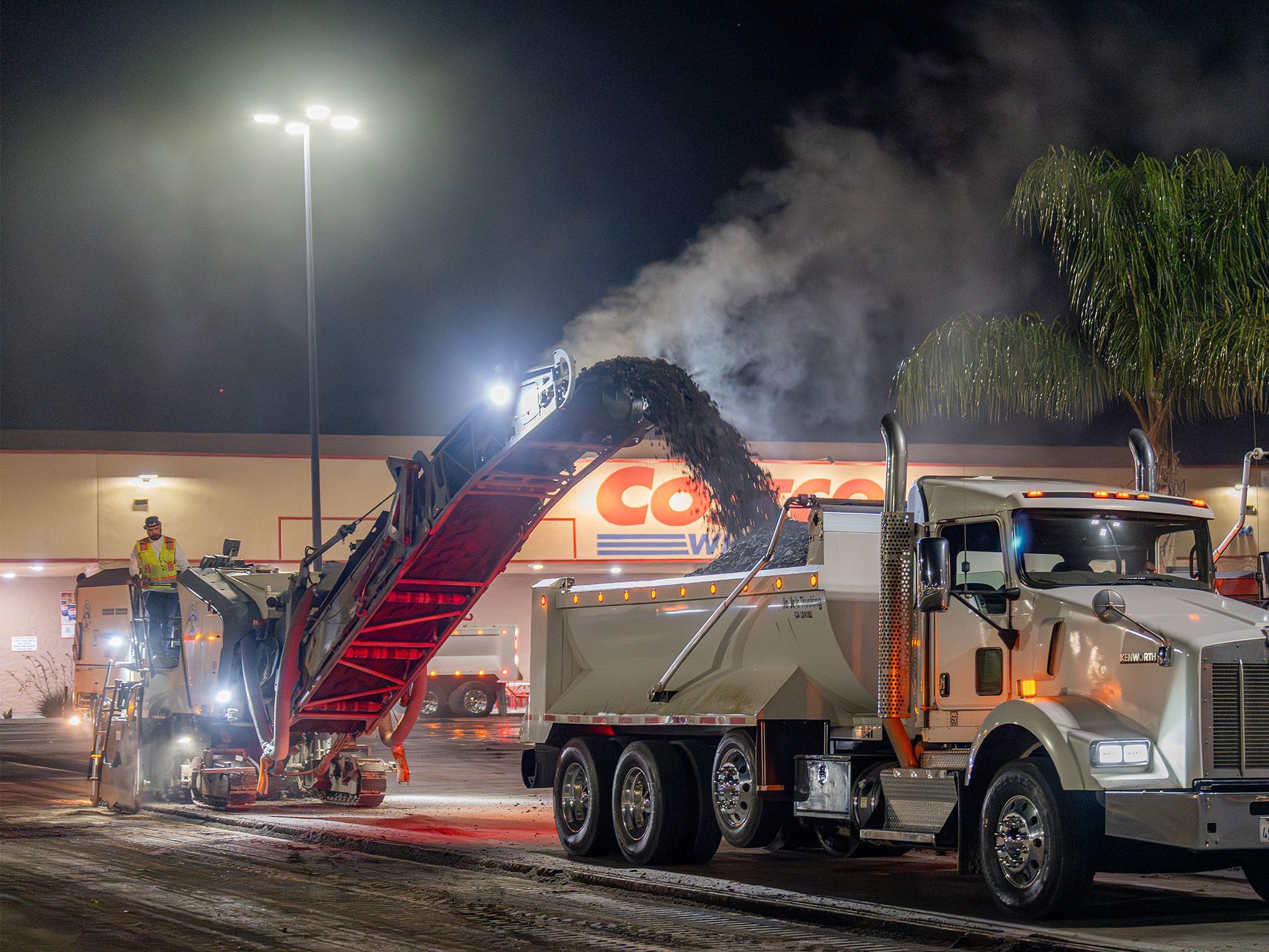 A dump truck is parked in front of a costco store at night.