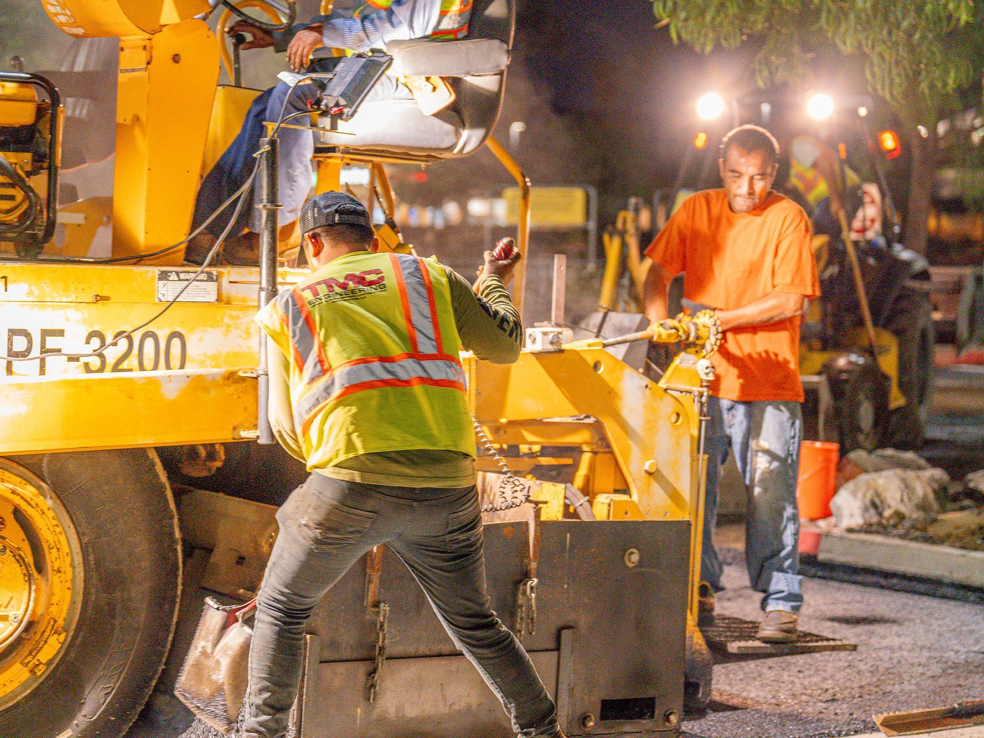 A group of construction workers are working on a road at night.