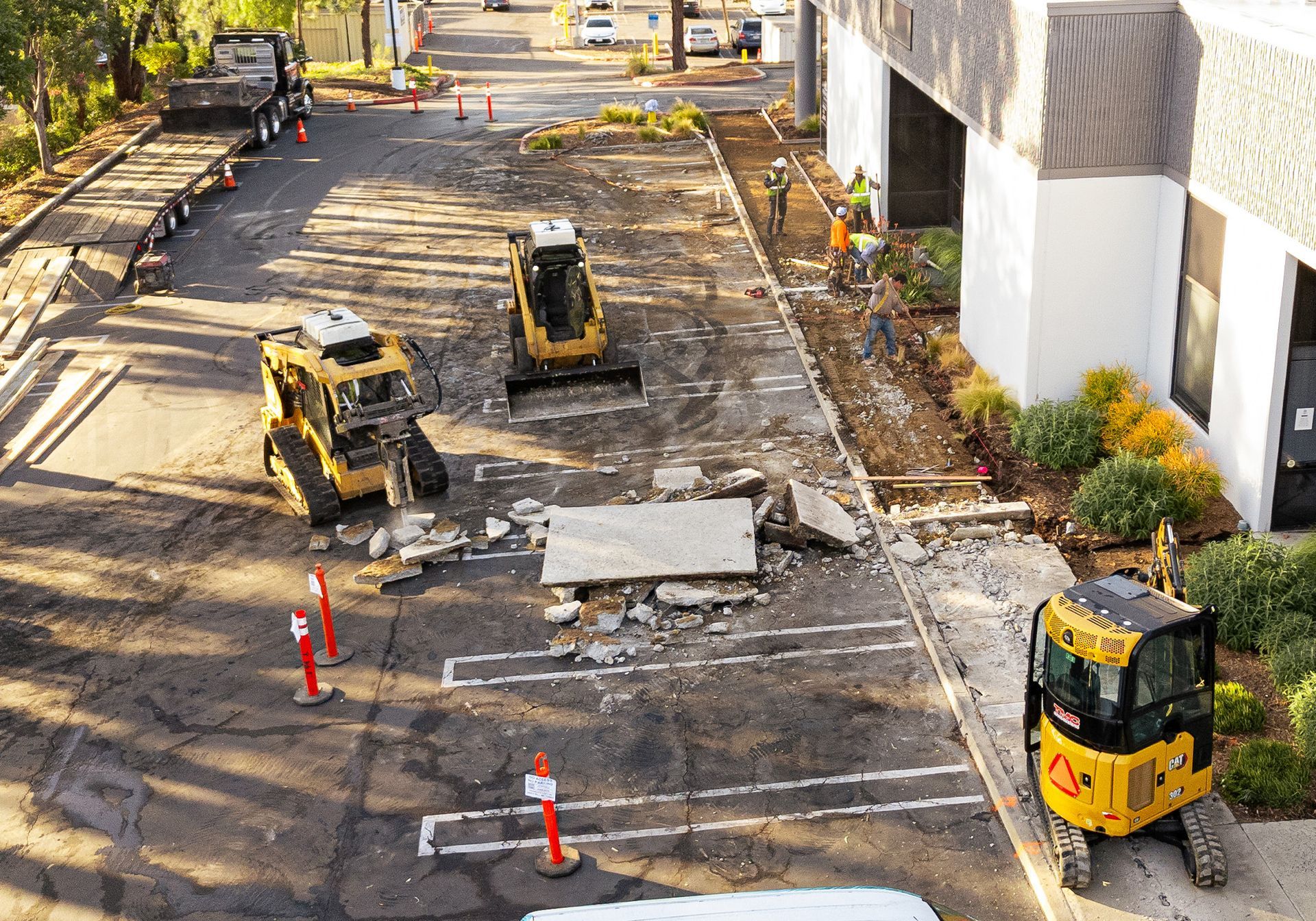 A group of construction vehicles are working on a parking lot.