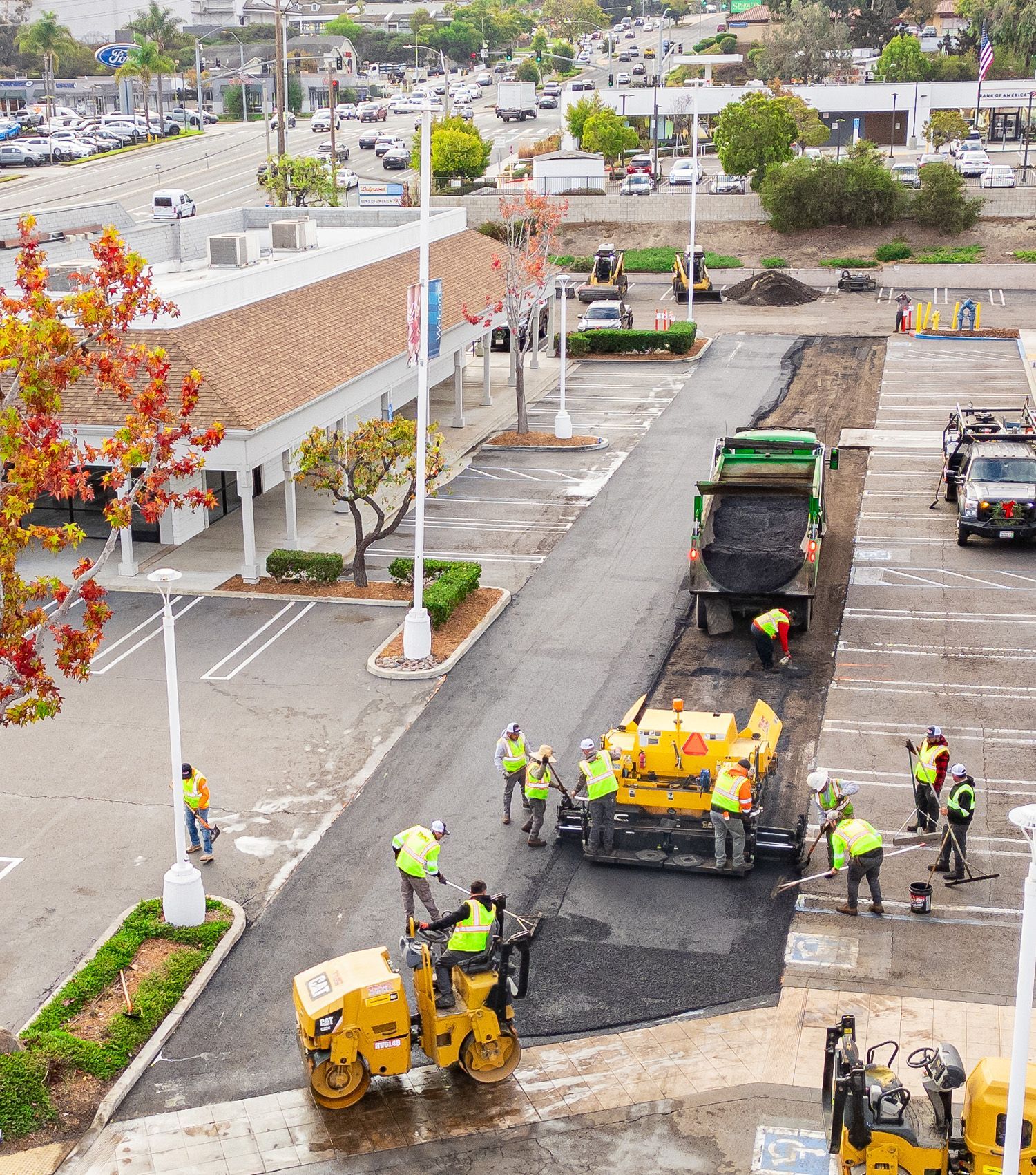 A group of construction workers are working on a road in a parking lot.