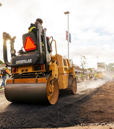 A man is driving a caterpillar roller on a road