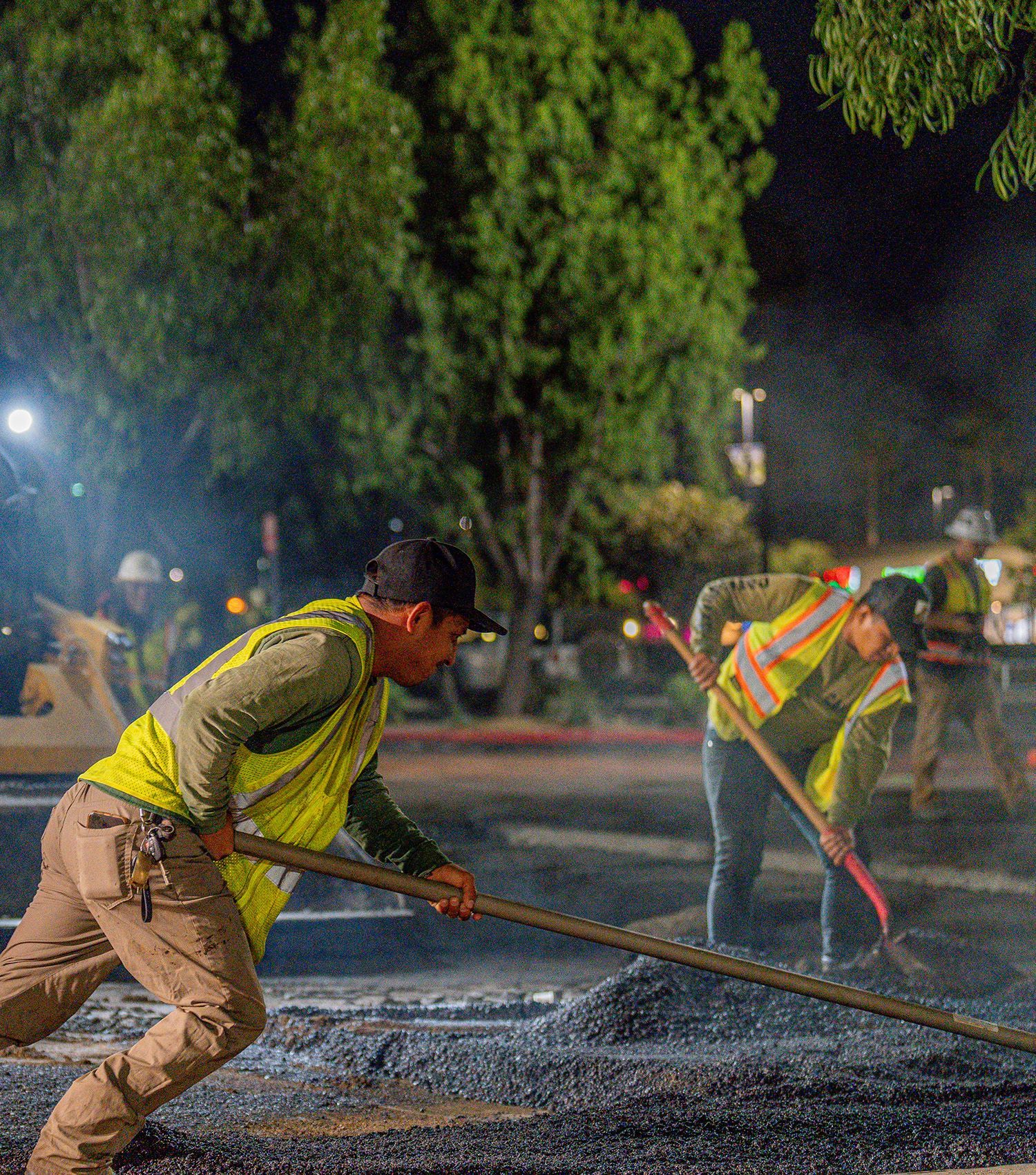 A group of construction workers are working on a road at night.