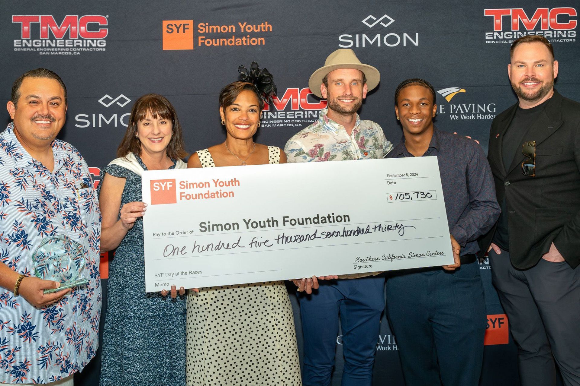 A group of people holding a large check for the simon youth foundation