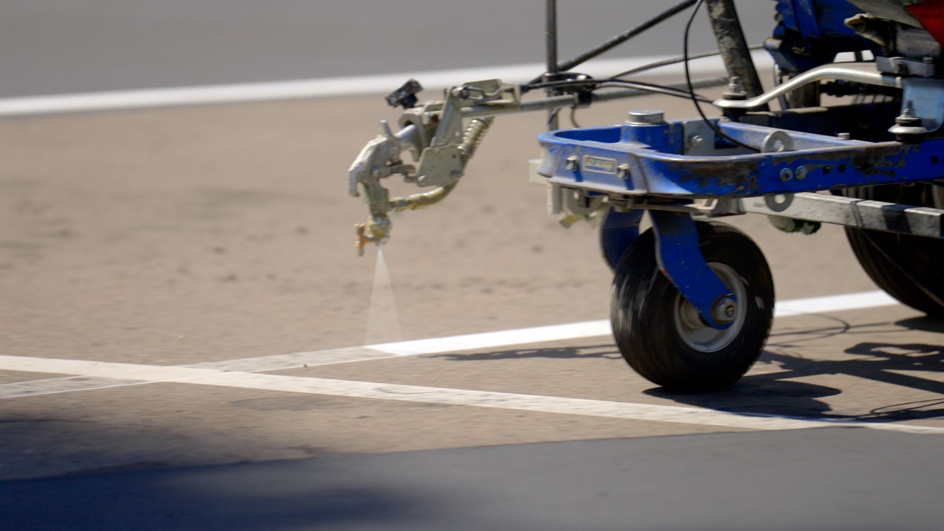 A machine is spraying white paint on a road.