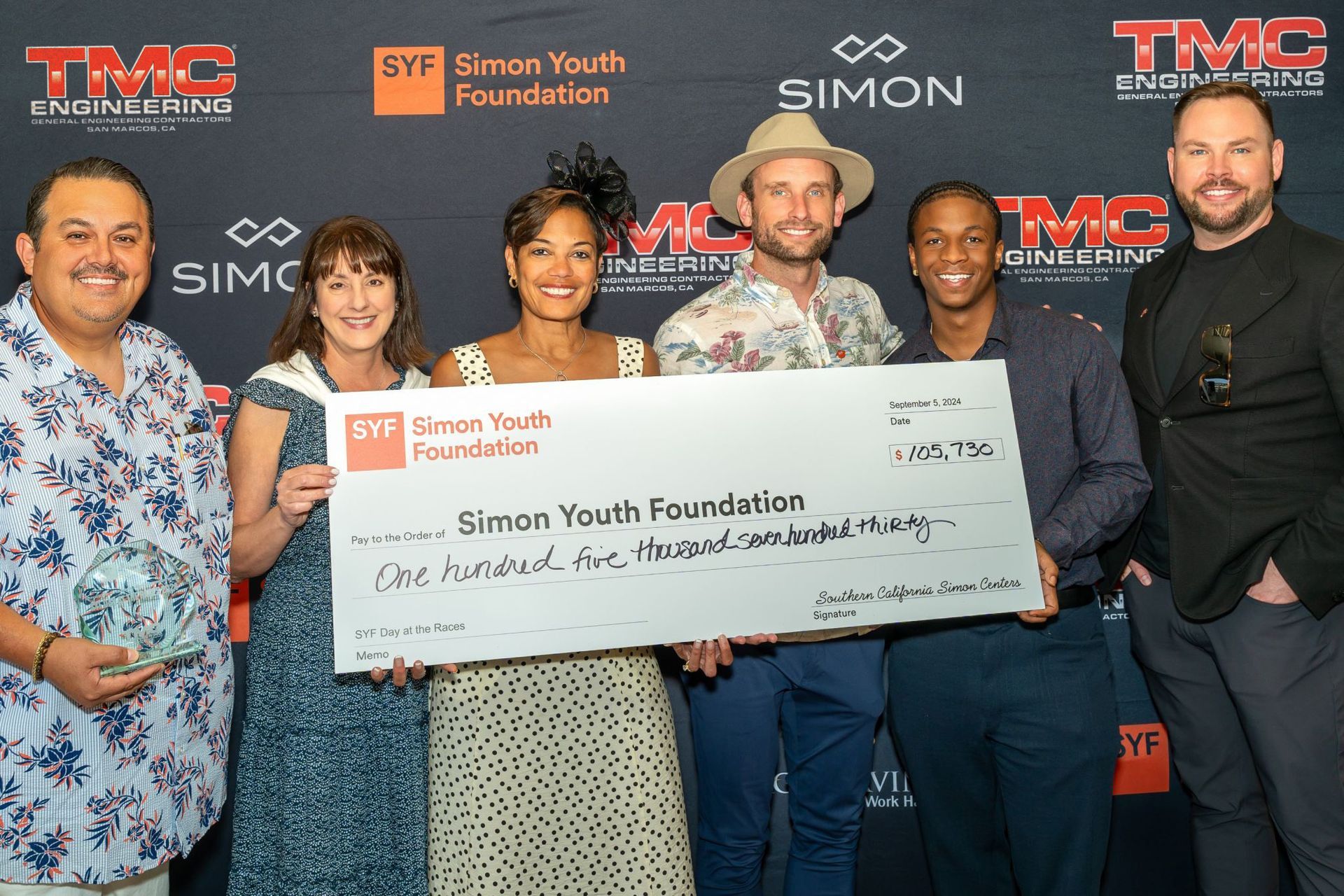 A group of people holding a large check for the simon youth foundation
