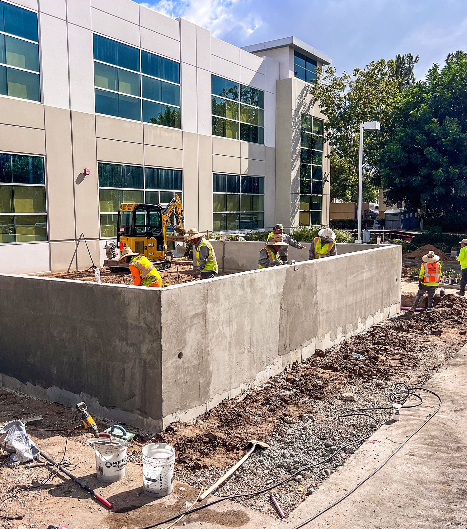 A group of construction workers are working on a wall in front of a large building