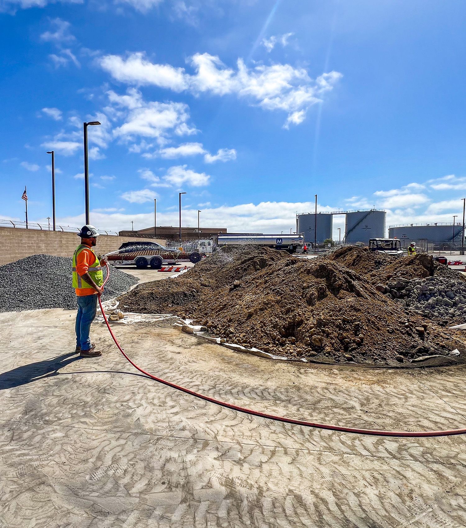 A construction worker is standing in front of a large pile of dirt.
