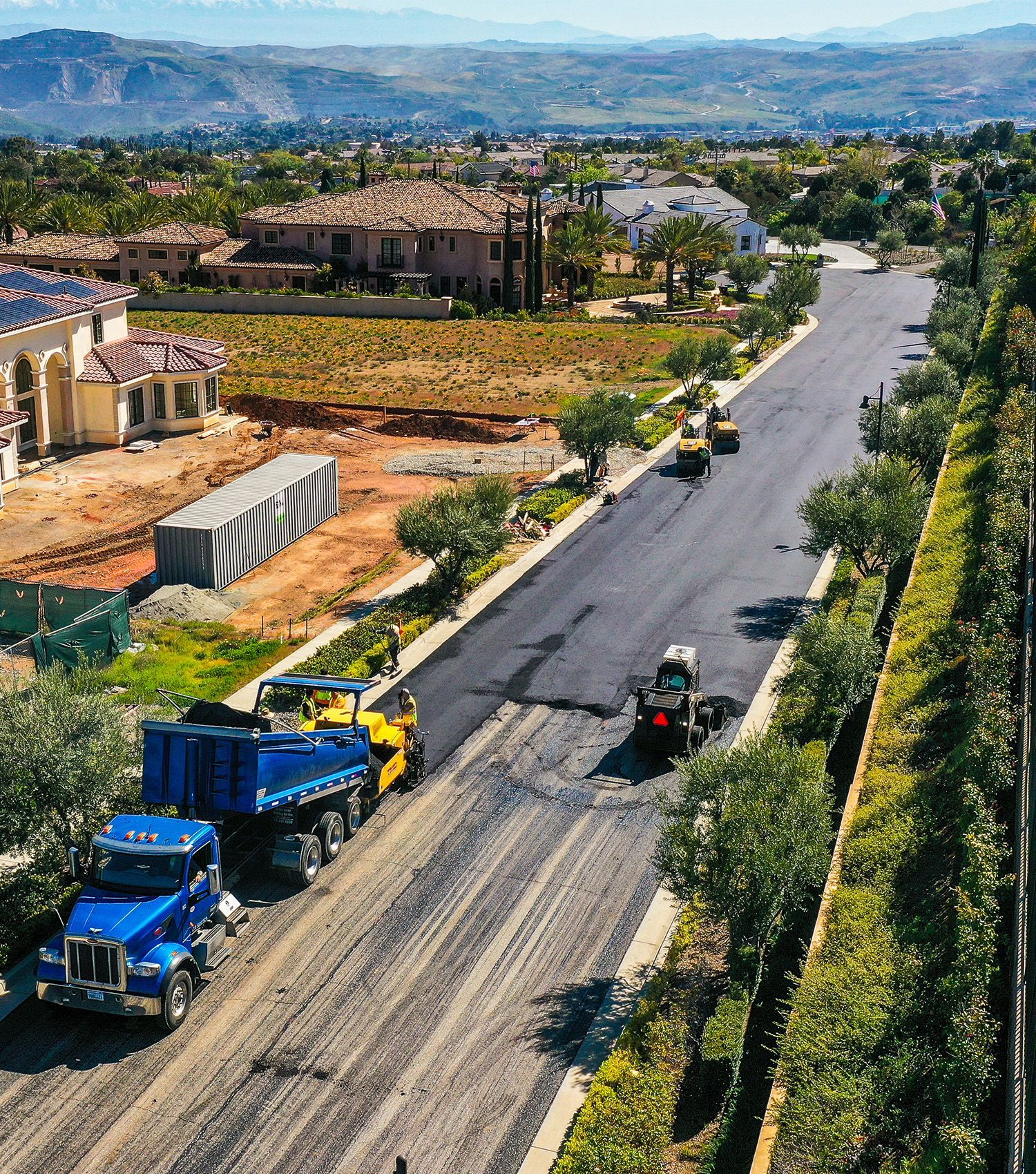 An aerial view of a road under construction with trucks and tractors.