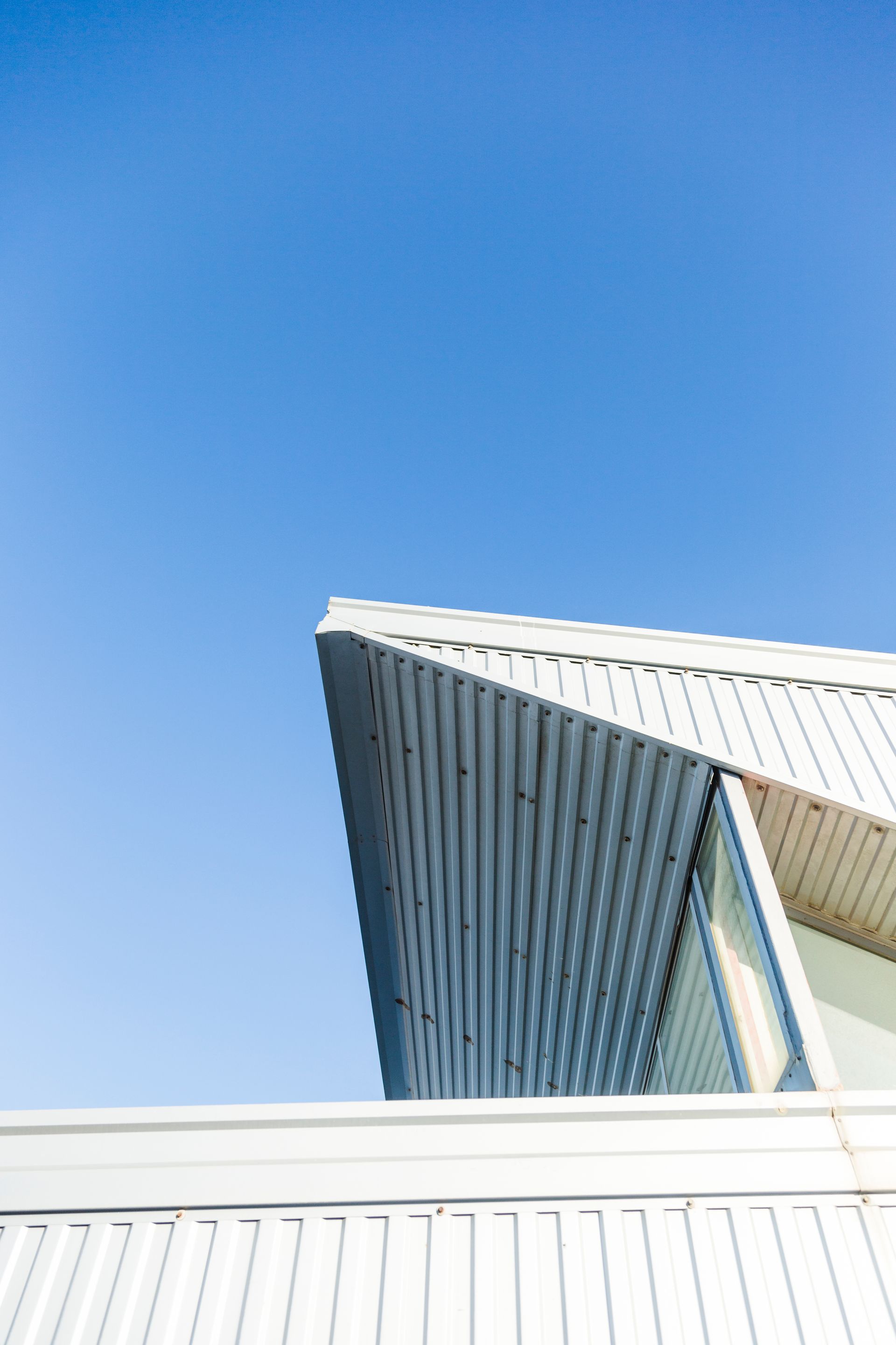 Looking up at the roof of a building with a blue sky in the background.