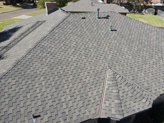 An aerial view of a roof of a house with a gray shingle roof.