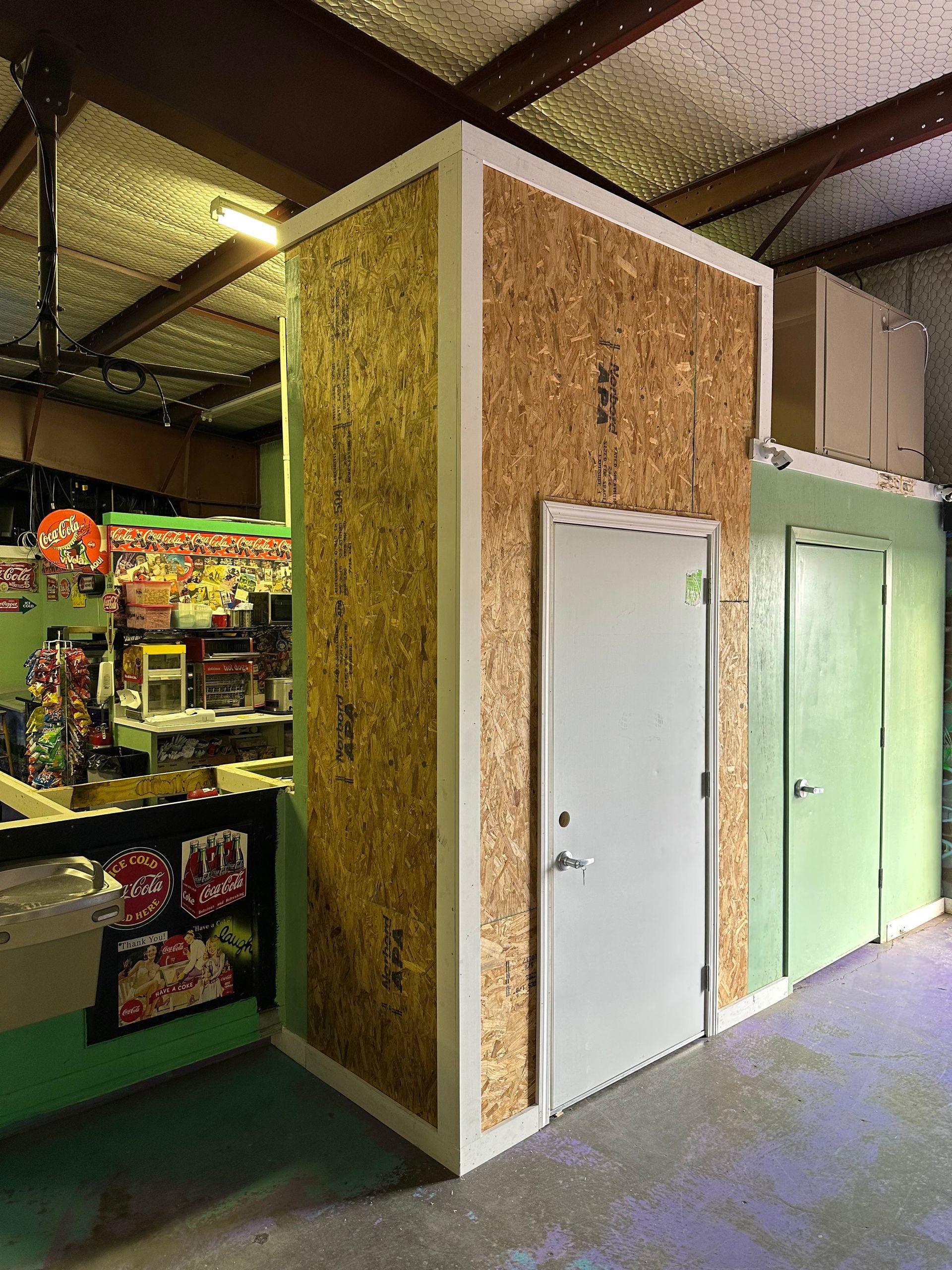 a room with a door and a wall made of plywood .