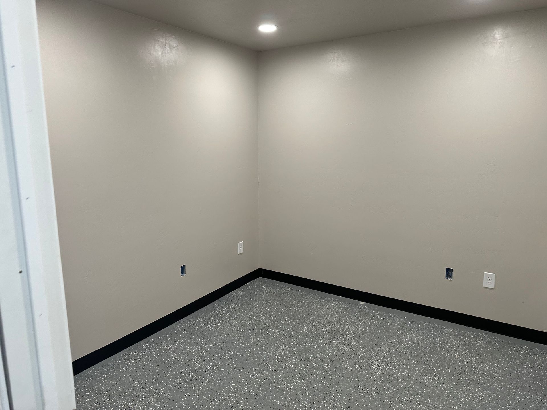an empty room with a gray floor and white walls .
