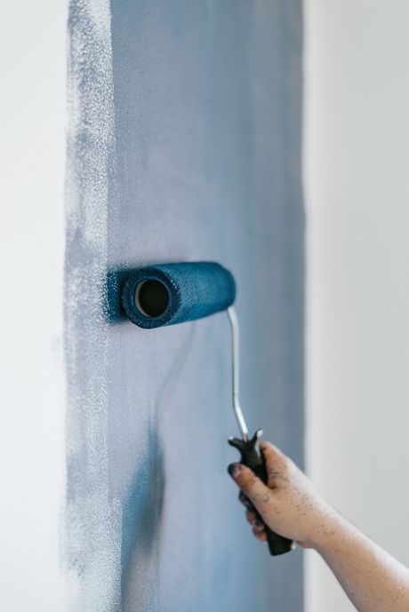 a person is painting a wall with a blue paint roller .