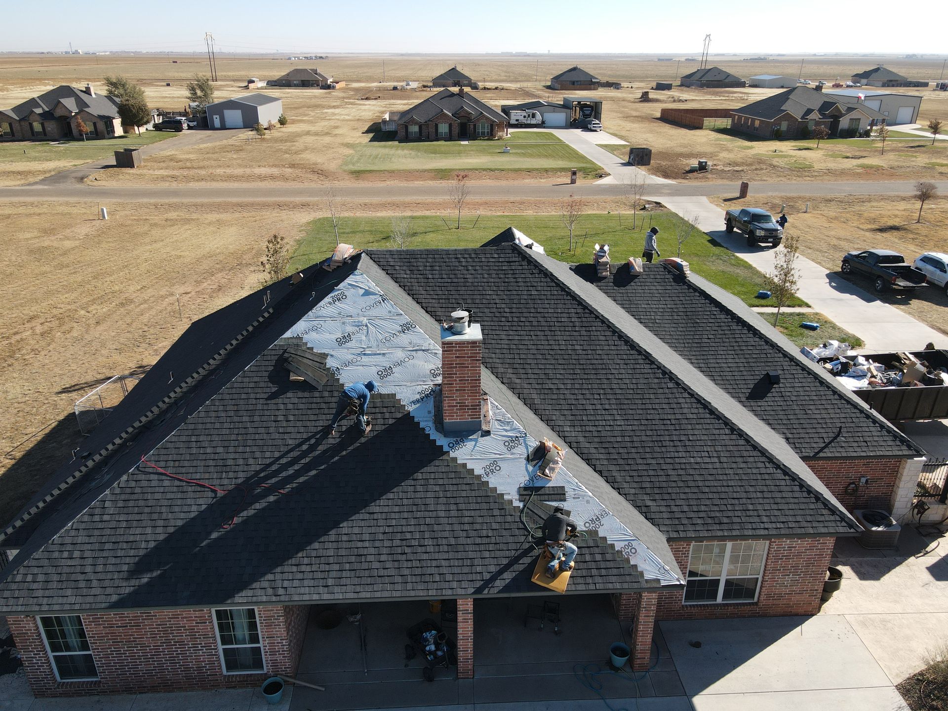 an aerial view of a house with a new roof being installed .