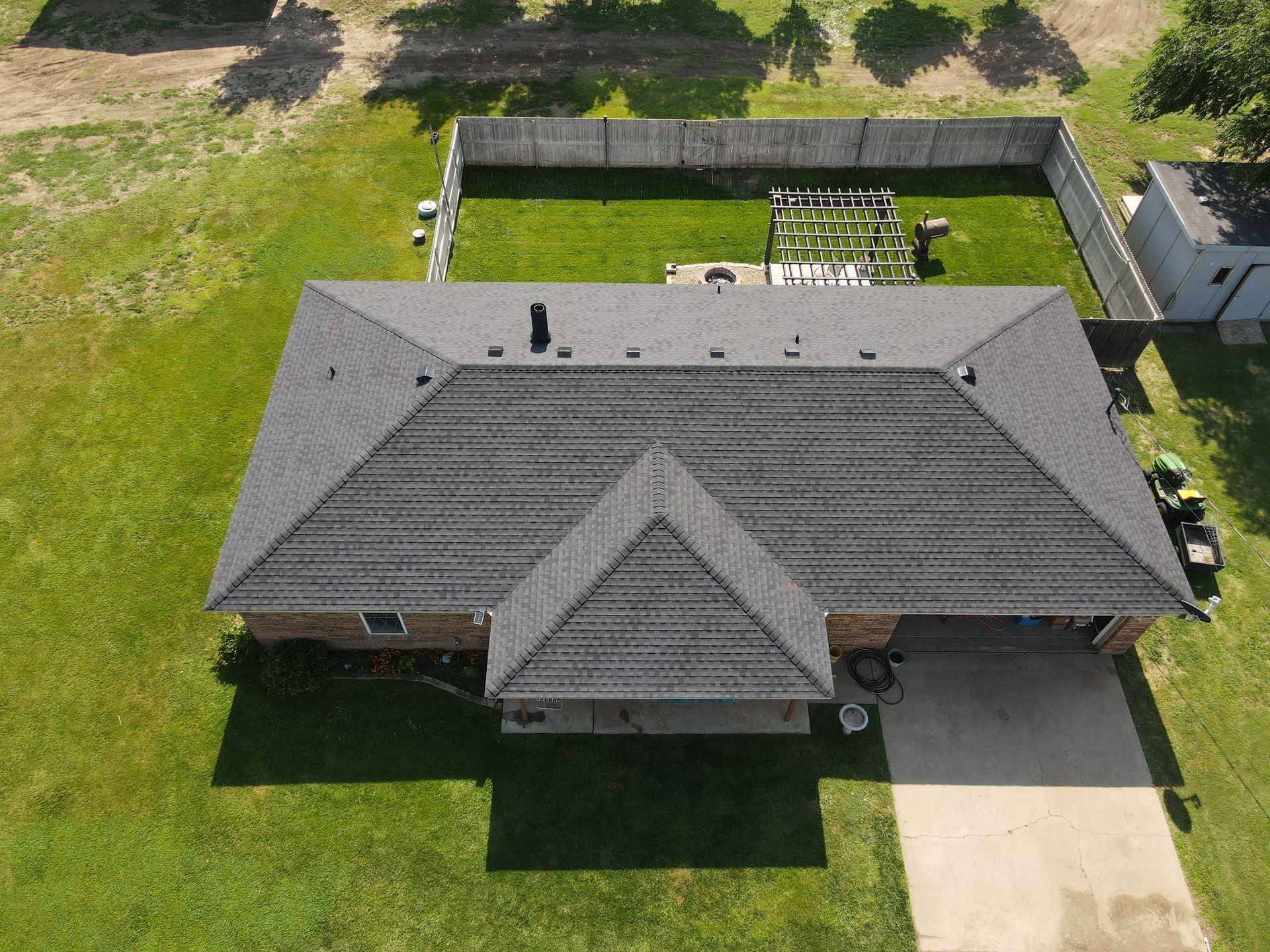 an aerial view of a house with a roof and a fence in the backyard .