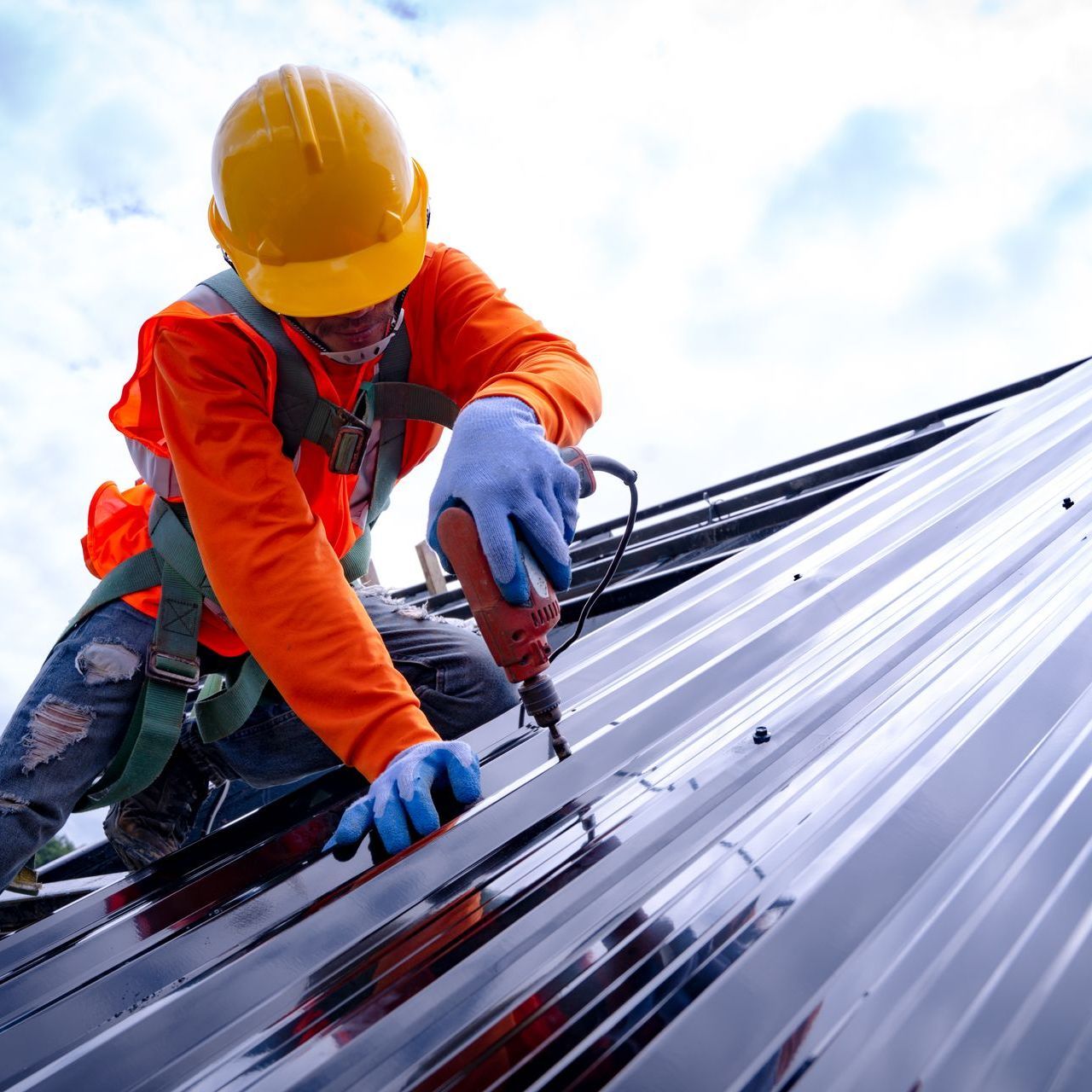 a man wearing a hard hat is working on a metal roof