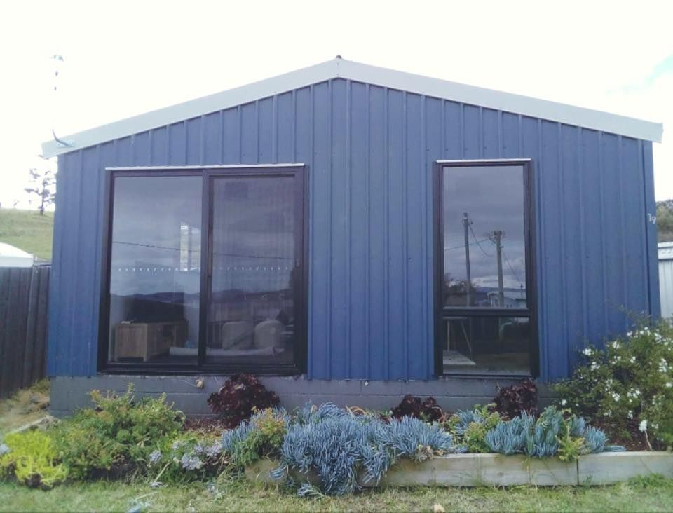 A blue house with a lot of windows and plants in front of it.