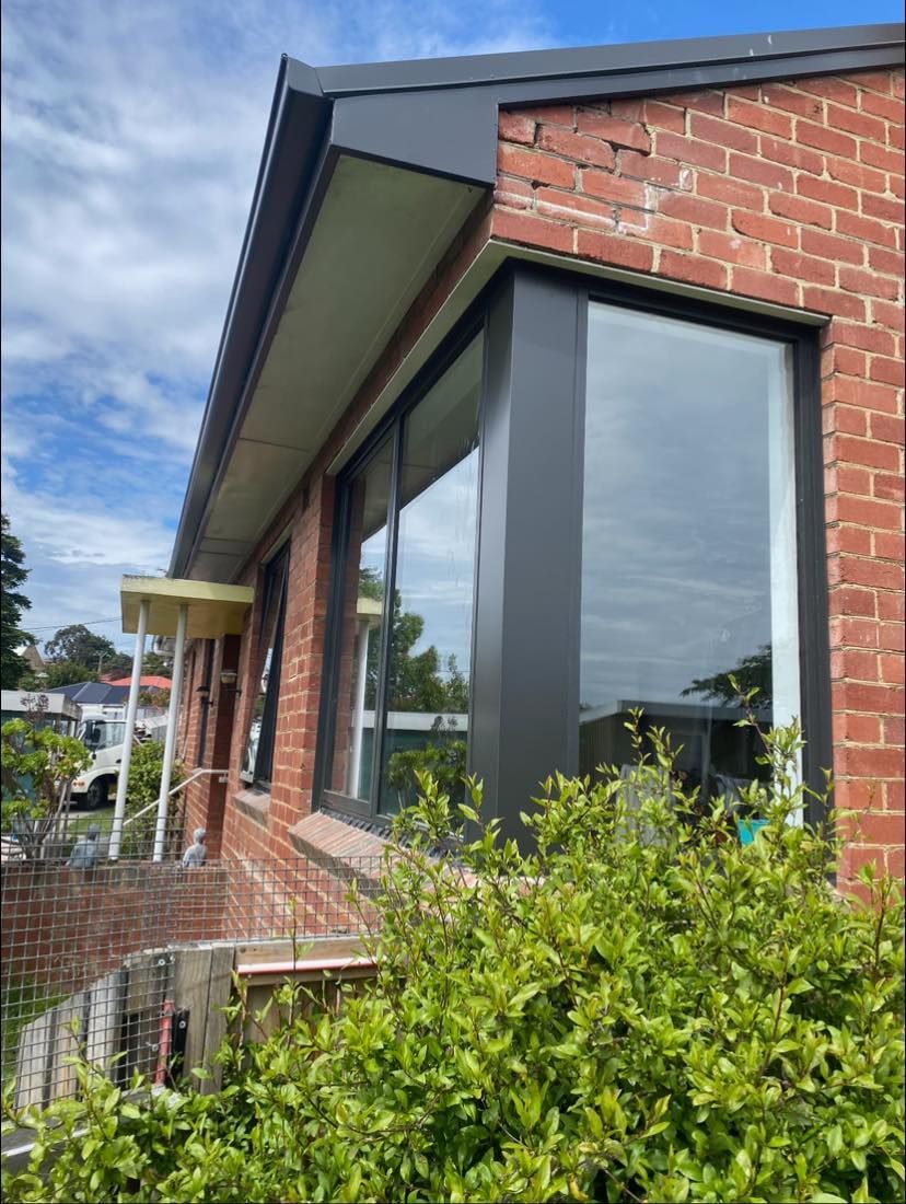 A brick building with a large window and a bush in front of it.