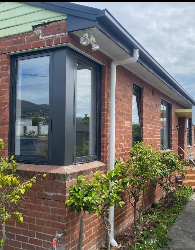 A brick house with a black window and a white gutter