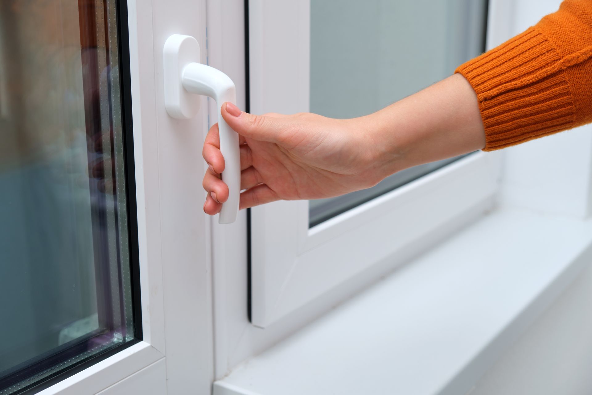 Female hand on a window handle, closing or opening a modern double-glazed window.