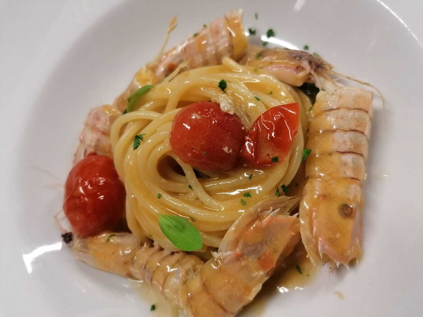 Un piatto bianco condito con spaghetti gamberi e pomodori