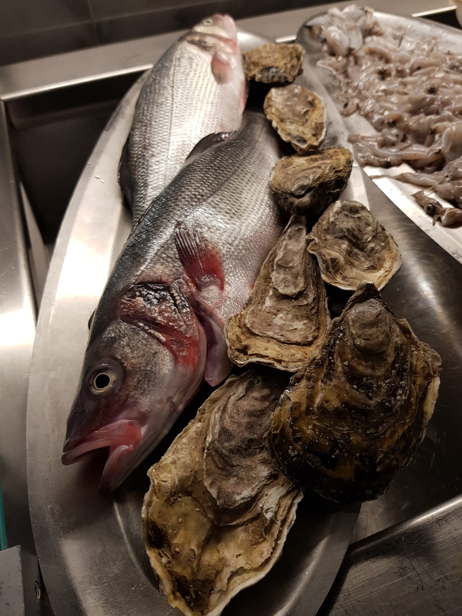 Un piatto di pesce e ostriche su un tavolo.