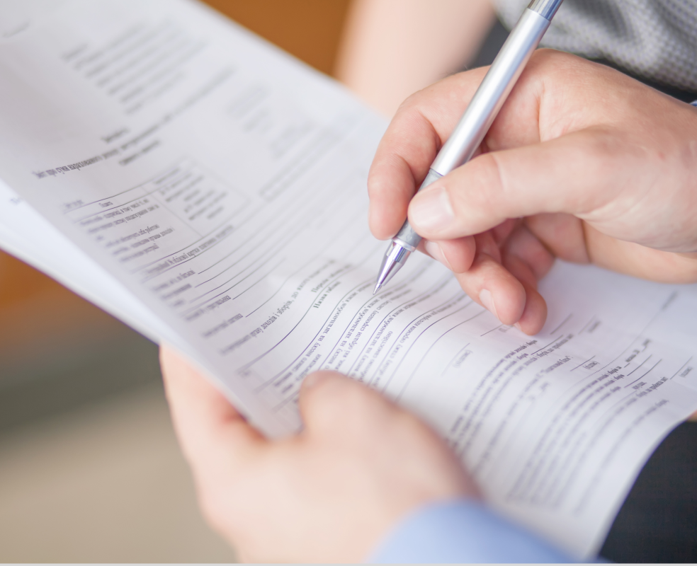 A person is writing on a piece of paper with a pen