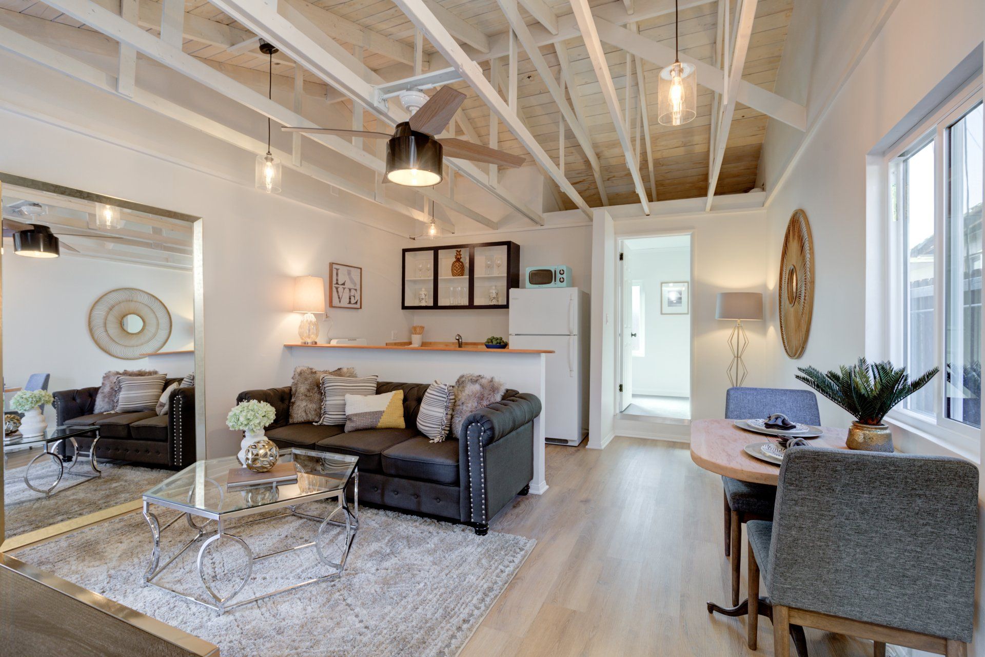 A living room with a couch , table , chairs and a mirror.