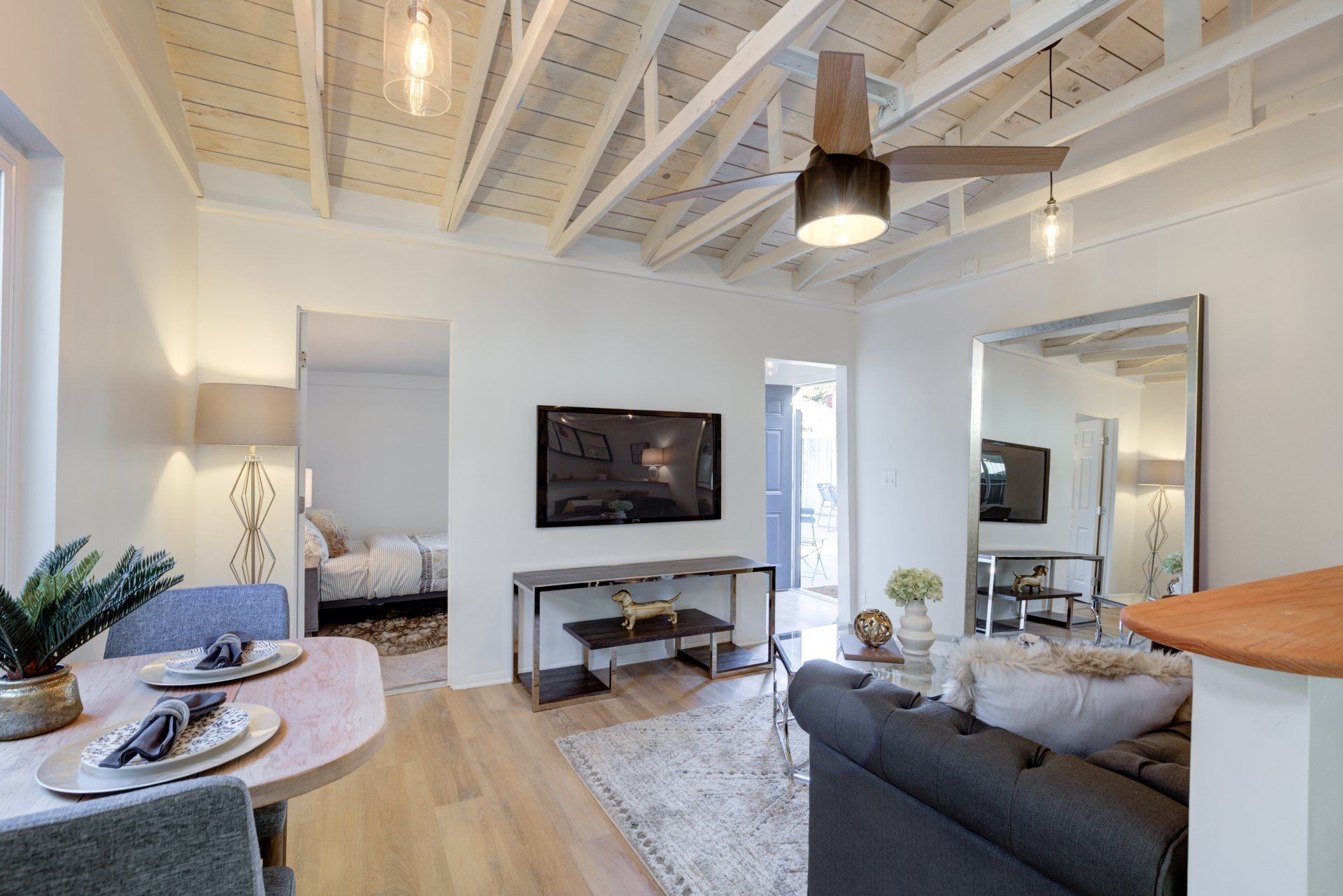 A living room with a couch , table , chairs and a television on the wall.