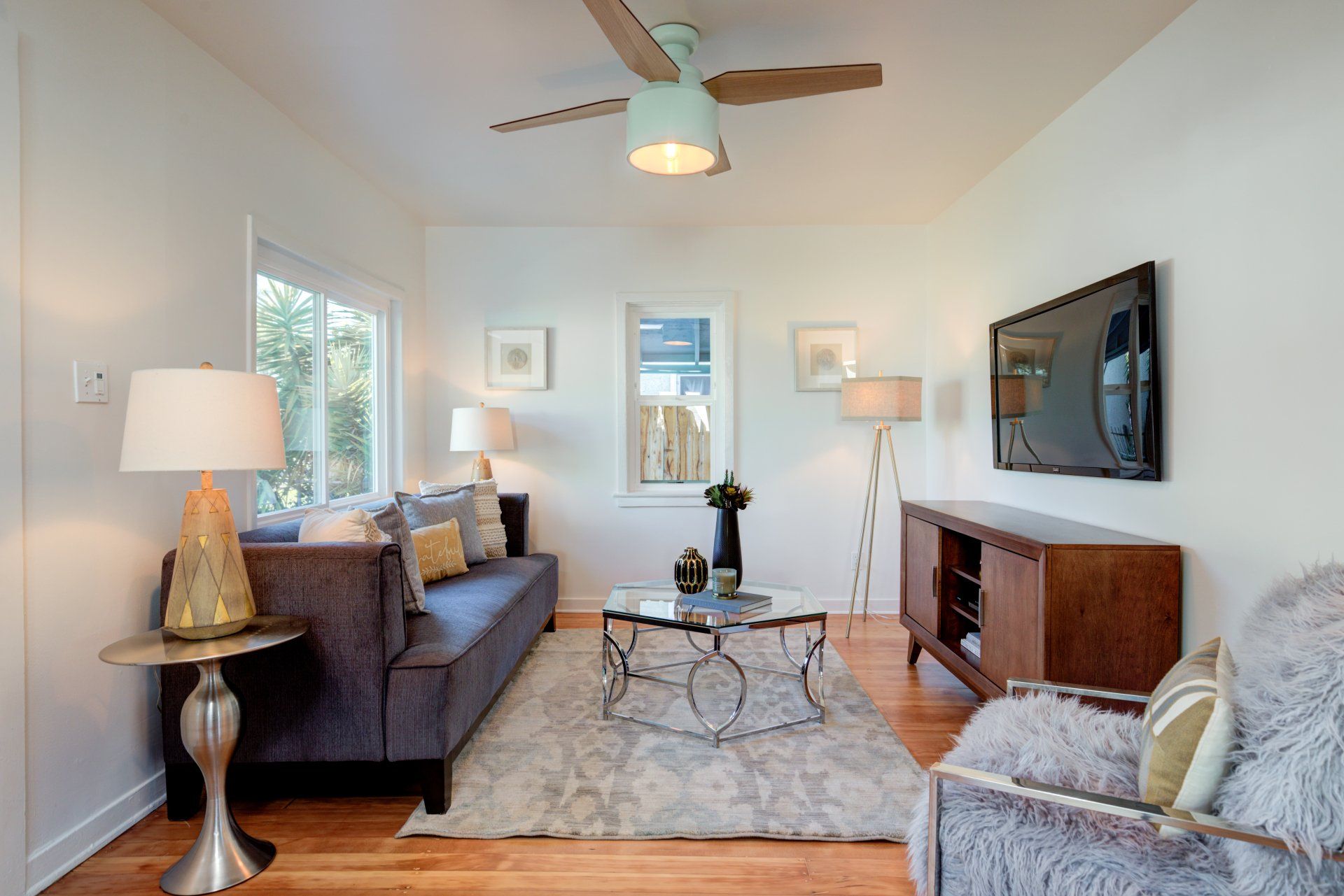 A living room with a ceiling fan and a flat screen tv