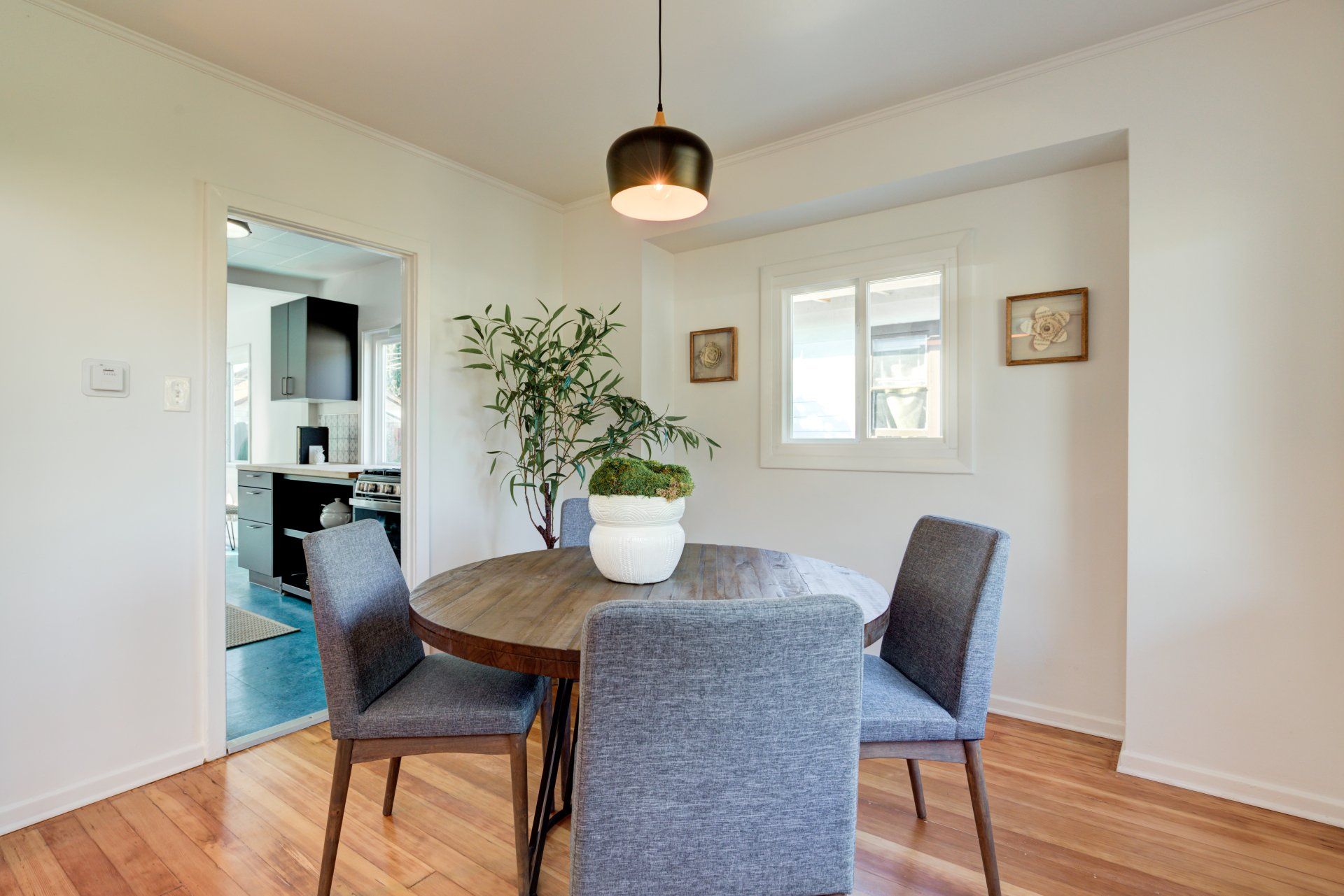A dining room with a round table and chairs and a potted plant.