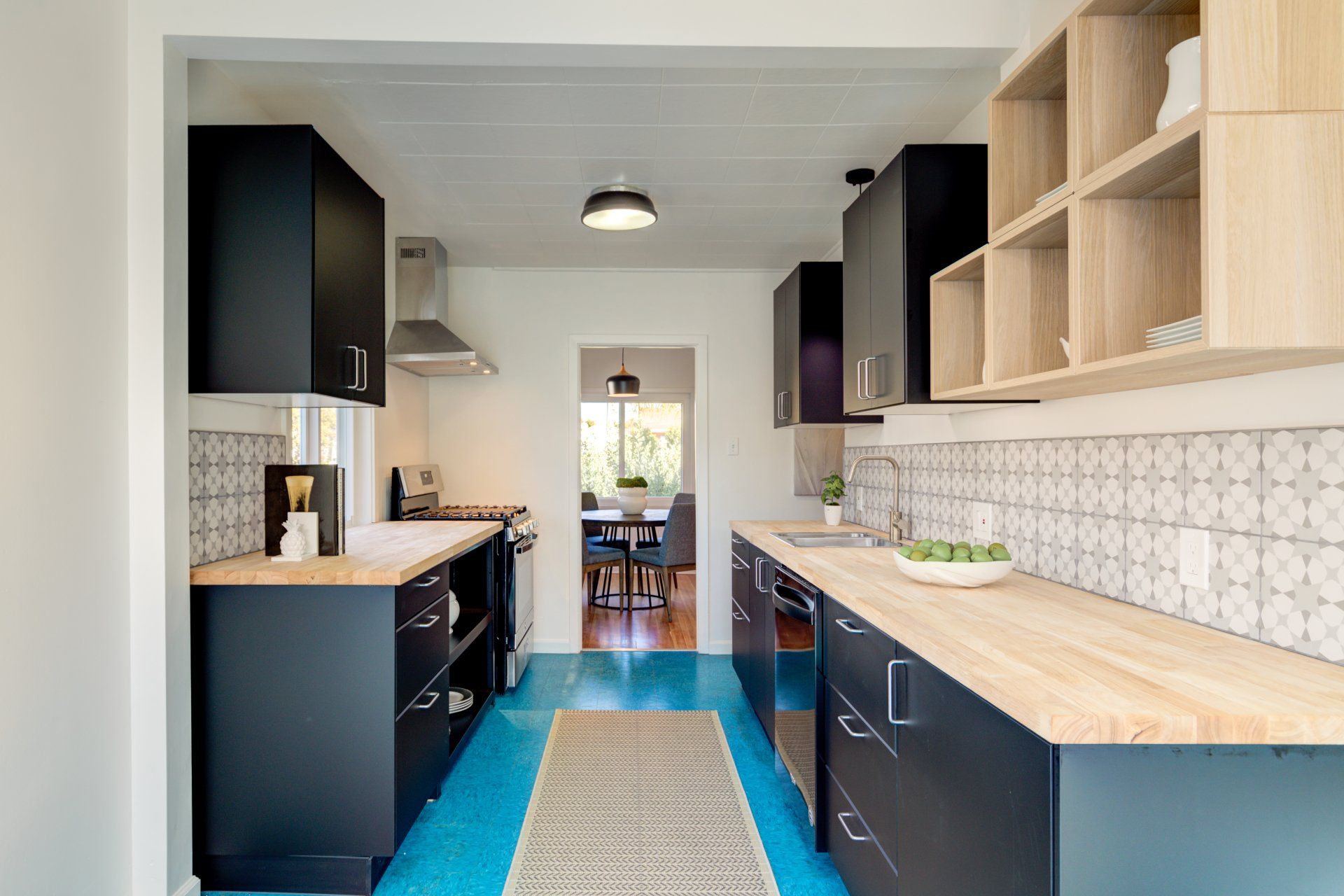 A kitchen with black cabinets , wooden counter tops , and a blue floor.