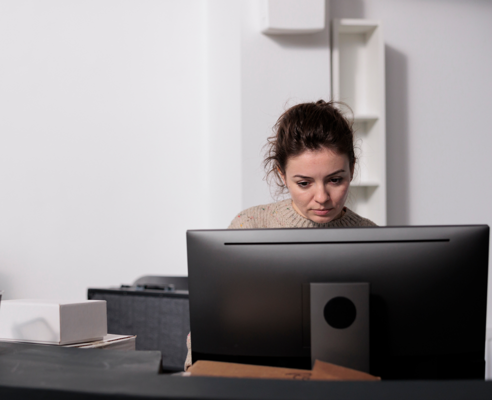 A woman is sitting in front of a computer monitor.