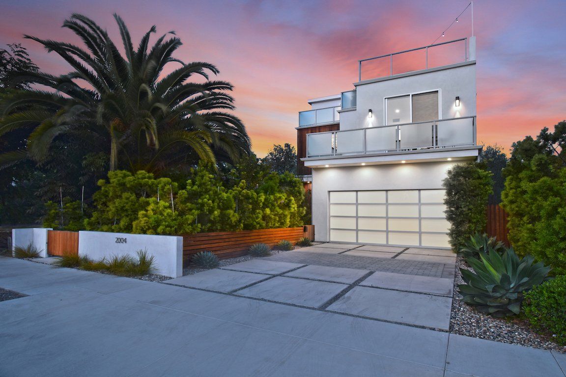 A white house with a garage and a balcony at sunset