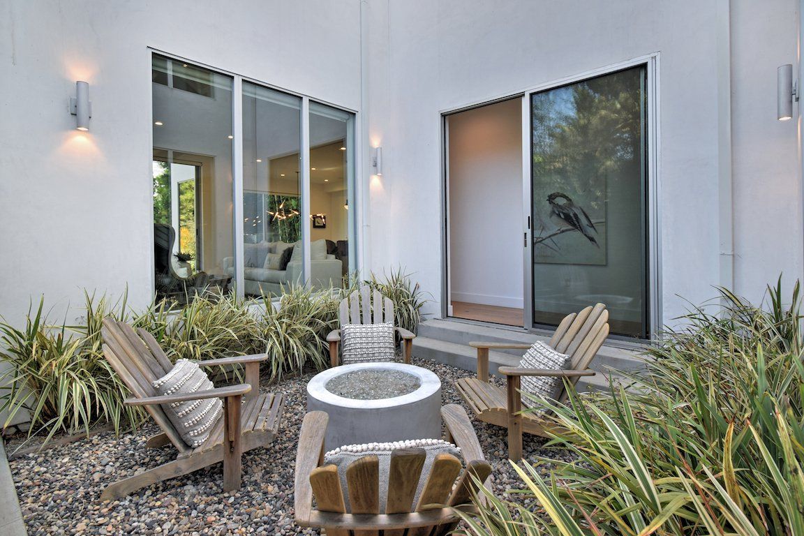 A patio with chairs and a fire pit in front of a house.