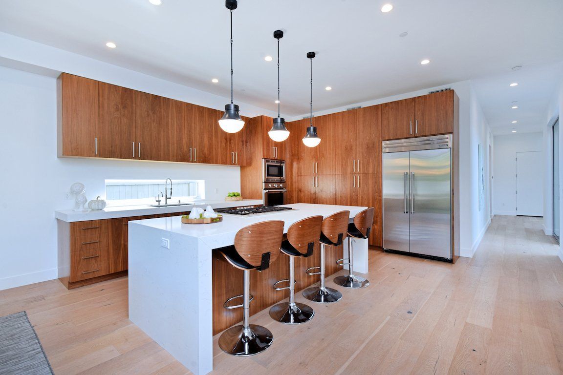 A kitchen with wooden cabinets , stainless steel appliances , and a large island.