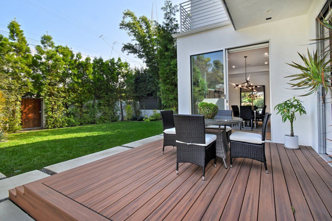There is a wooden deck with a table and chairs on it.