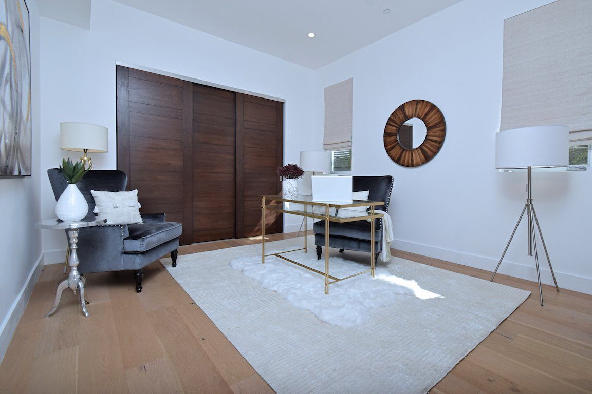 There is a clock on the wall above the desk in the room.