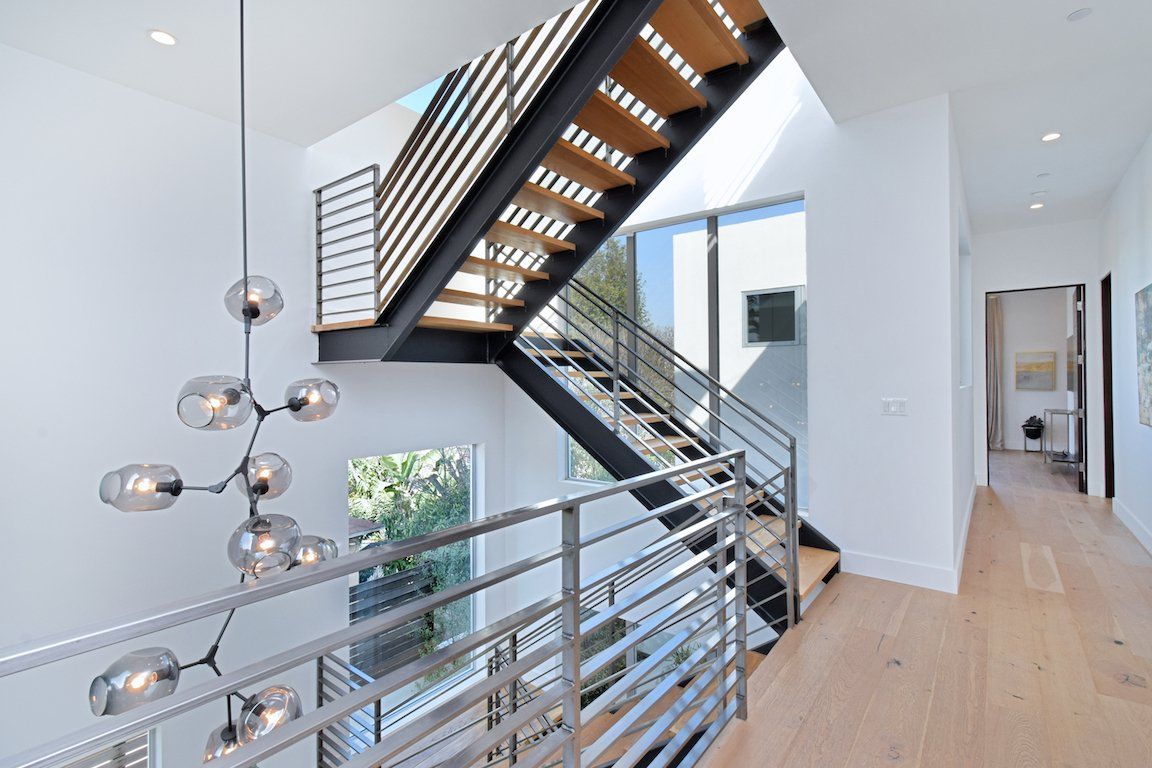 A modern staircase in a house with a stainless steel railing