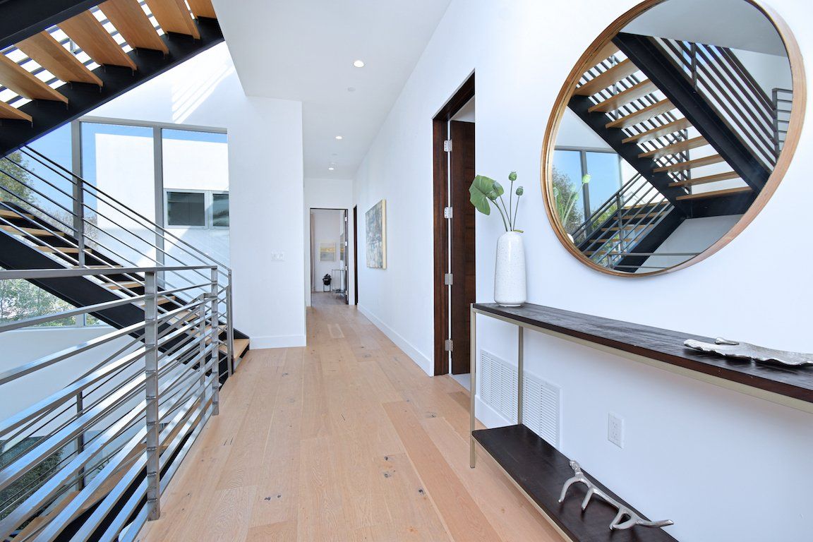 A hallway with two mirrors and stairs in the background