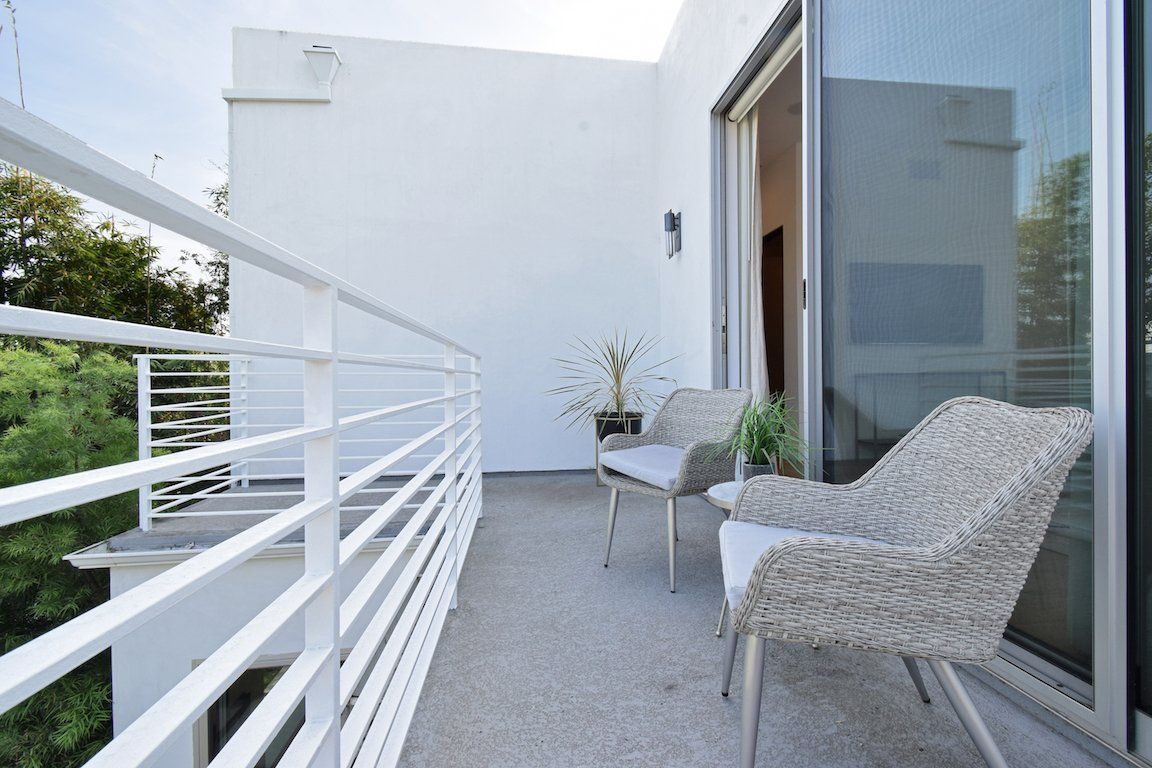 A balcony with two chairs and a table with a white railing
